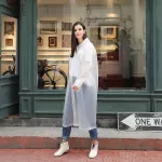 A woman who is not used and throws a large white rain shirt